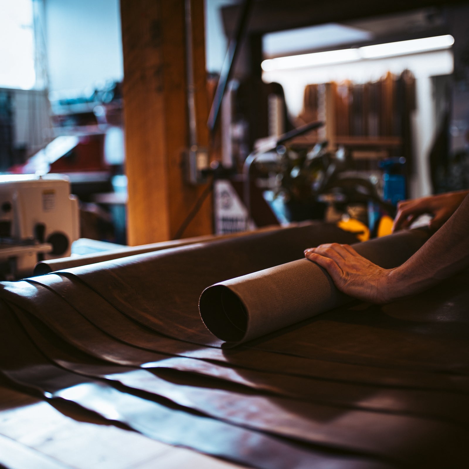 A man rolling out a large tube of aniline leather